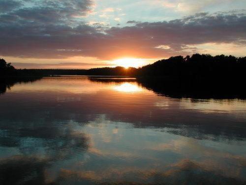 a sunset on a lake with the sun setting at Mobilheim Zweiundvierzig In Lychen in Lychen