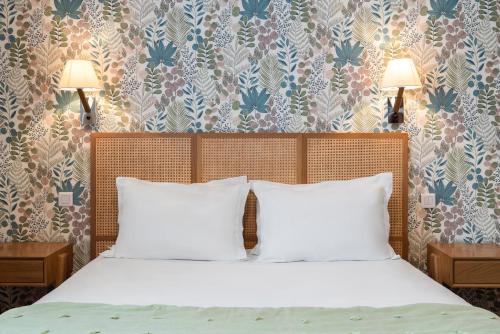 a bedroom with a bed with white pillows and wallpaper at The Originals Boutique, Hôtel Normandie, Auxerre in Auxerre
