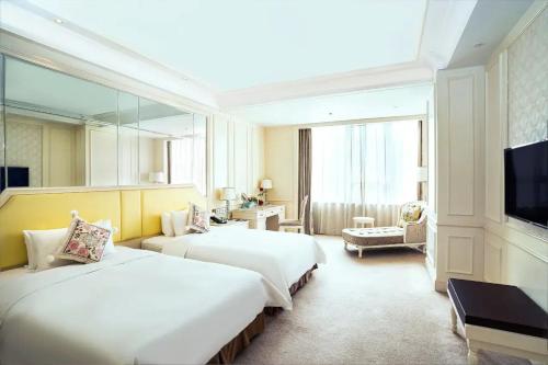 a hotel room with two beds and a flat screen tv at Gallery F Hotel in Wuhan