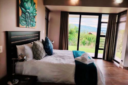 a bedroom with a large bed with a large window at Dierama Dream, Cathkin Estates - 4 adults and 2 children, 12 years or younger in Ardmore