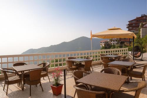 a patio with tables and chairs and an umbrella at Hotel Samrat - On Mall Road in Mussoorie