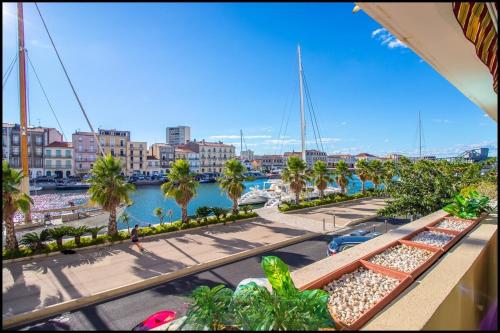 a view of a marina with palm trees and buildings at L'ariot 1984 - appartement cosy avec terrasse, parking et wifi in Sète