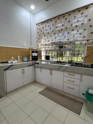 a kitchen with white cabinets and a sink at Magnolia 3 Homestay in Kampung Raja