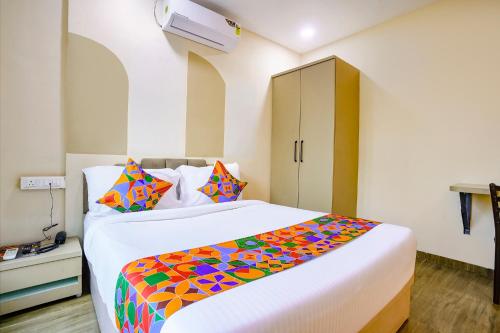 a bedroom with a large white bed with colorful pillows at FabHotel Melody NX in Thane