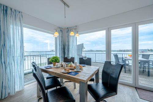 a dining room with a table and chairs and a balcony at Maisonette Fewo Kapteins Lounge by Seeblick Ferien ORO, Rundum Wasser, 6Pers, Sauna, Kamin in Olpenitz