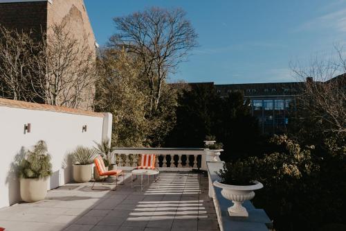 a patio with orange chairs and a white fence at Isidore in Bruges