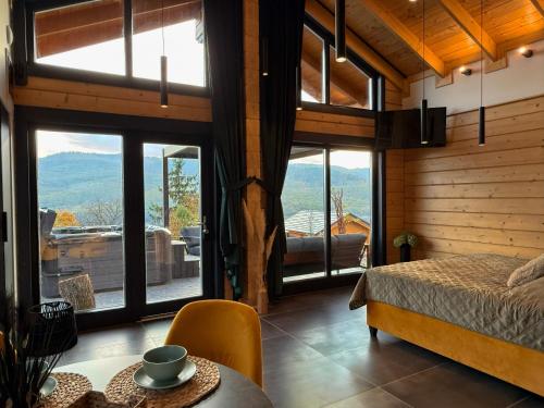 a bedroom with a bed and a table and some windows at Bükk Hill Garden in Miskolc