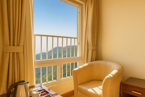 Habitación con silla y ventana grande. en Hotel Samrat - On Mall Road, en Mussoorie