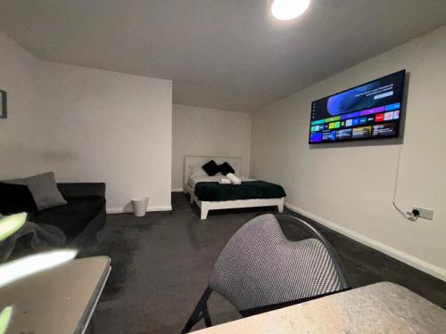 een woonkamer met een bed en een tv aan de muur bij Cosy Modern Studio Apartement in Ilkeston