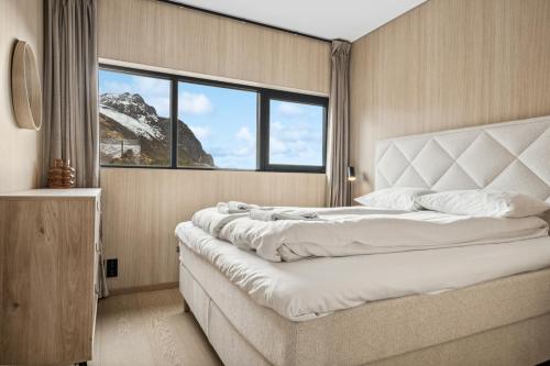 a bedroom with a large bed and a large window at Fjordview Arctic Lodge with sauna and Jacuzzi in Lyngværet
