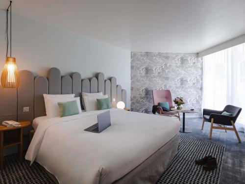 una habitación de hotel con una gran cama blanca y sillas en Mercure Aix-les-Bains Domaine de Marlioz Hôtel & Spa, en Aix-les-Bains