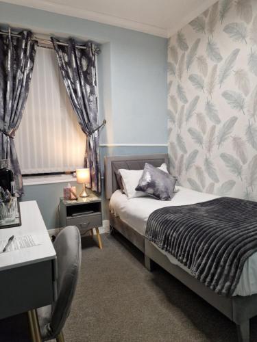 ペイントンにあるAmbassador Guest Houseのベッドと机と窓のある寝室