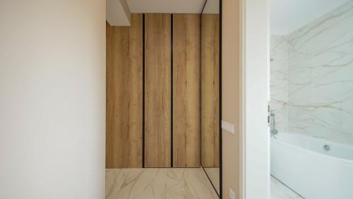 a bathroom with a wooden door next to a tub at Le Luna Apart in Braşov