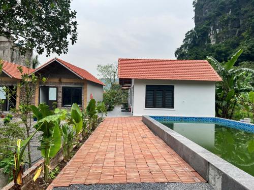 une maison avec une passerelle en briques à côté d'une piscine dans l'établissement Tam Coc Mountain Light Homestay, à Ninh Binh