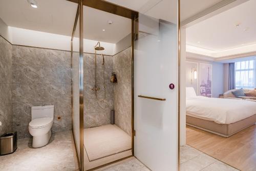 a bathroom with a shower and a toilet and a bed at Mercure Hohhot Downtown in Hohhot