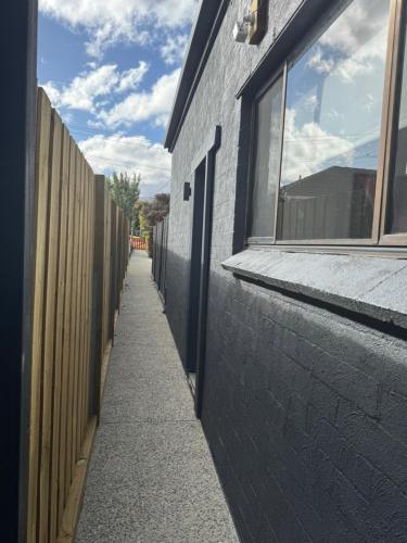 a sidewalk next to a building with a fence at Little Red Gate Urban Retreat in Kingston