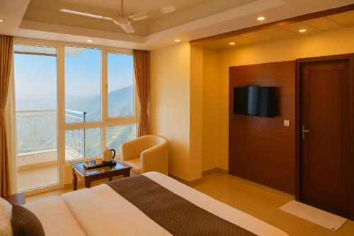 una habitación de hotel con una cama y una ventana grande en Hotel Samrat - On Mall Road, en Mussoorie