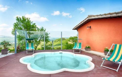 a hot tub on a deck with two chairs and a house at 2 Bedroom Nice Apartment In Sant'angelo In Vado in Piandimeleto