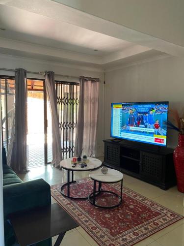 a living room with a tv and a couch and a table at Ubuntu Guest House in Cape Town