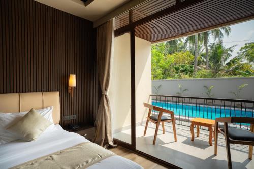 1 Schlafzimmer mit einem Bett und einem Balkon mit einem Pool in der Unterkunft The Coral Bentley Hotels in Havelock Island
