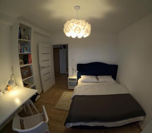 a bedroom with a bed and a desk and a chandelier at Apartament Rutkiewicz in Łańcut