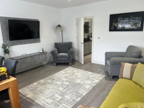 a living room with a couch and two chairs and a flat screen tv at Nest in Northumberland in Blythe