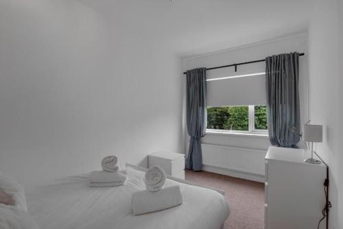 a white bedroom with a bed and a window at Pass the Keys Seaside Sanctuary Cullercoats – Walk to the Beach in Cullercoats