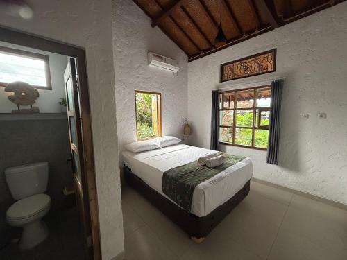 a bedroom with a bed and a toilet and a window at Nextdoor Rooms in Yogyakarta