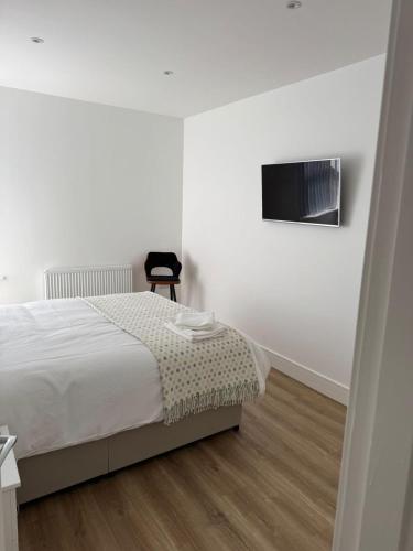 a white bedroom with a bed and a chair at Nest in Northumberland in Blythe