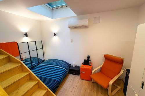 ein Schlafzimmer mit einem Bett und eine Treppe mit einem Stuhl in der Unterkunft Superbe appartement sur jardin- proche de paris in Vanves