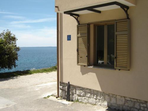 a window on a building with a view of the ocean at Gemütliches Appartment Direkt Am Strand in Koromačno