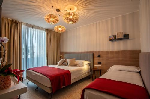 a hotel room with two beds and chandeliers at Hotel Sirenetta in Grado
