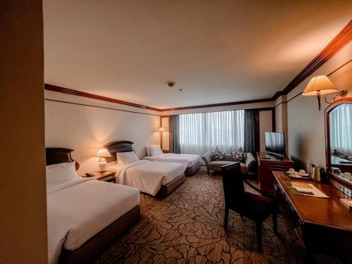 a hotel room with two beds and a desk at The Twin Lotus Hotel in Nakhon Si Thammarat