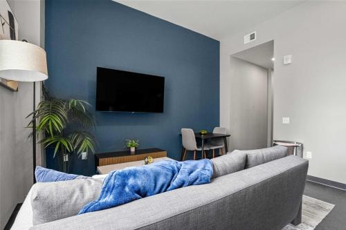 sala de estar con sofá y TV en una pared azul en CozySuites Modern 1BR Downtown Pitts 10, en Pittsburgh