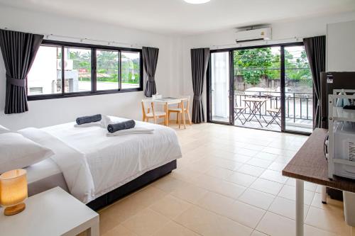 a bedroom with a bed and a balcony with a table at Stay White Orchid in Krabi