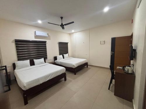 a hotel room with two beds and a ceiling fan at Casa Grand in Alwaye