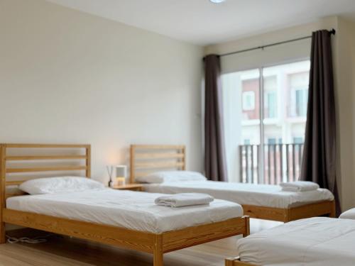 three beds in a room with a window at Jira cozy room Suvarnabhumi Airport 15mins in Lat Krabang