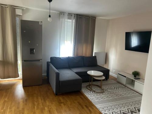 ein Wohnzimmer mit einem blauen Sofa und einem Tisch in der Unterkunft Omega Appartment in Corbeil-Essonnes