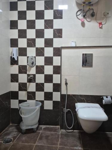 baño con aseo y pared a cuadros en Hotel Raveena 12, en Nueva Delhi