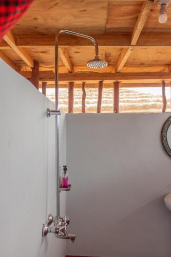 a shower in a bathroom with a wooden ceiling at Naramatisho Womens Centre & Maasai Cultural Stay in Makuyuni