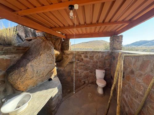 a stone bathroom with a toilet and a sink at Nauams Namibia - Farmyard Chalets, Mountain Cabins and Campsite in Namibgrens