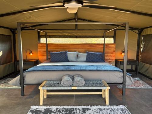 a bedroom with a canopy bed with a table at Nauams Namibia - Farmyard Chalets, Mountain Cabins and Campsite in Namibgrens