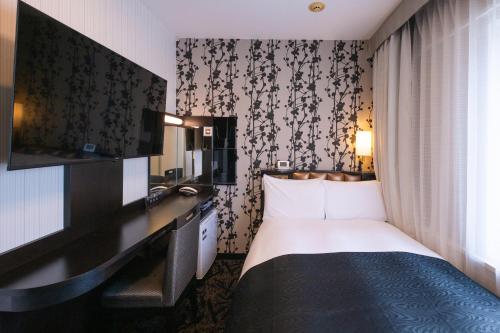 a hotel room with a bed and a flat screen tv at APA Hotel Nagoya Marunouchi Ekimae in Nagoya
