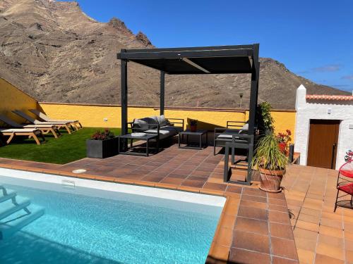 eine Terrasse mit Stühlen, einem Tisch und einem Pool in der Unterkunft Ferienhaus für 4 Personen und 2 Kinder in Urb La Suerte, Gran Canaria Westküste Gran Canaria in Agaete
