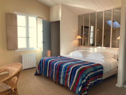 a bedroom with a large bed with a striped blanket at Hôtel Le Sénéchal in Ars-en-Ré