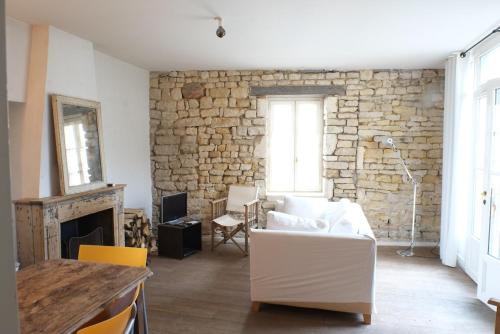 a living room with a white couch and a stone wall at Hôtel Le Sénéchal in Ars-en-Ré