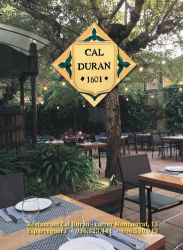 a sign for a cal dumani restaurant hanging from a tree at Hostal Restaurant Cal Duran in Esparraguera