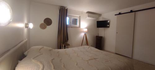 Un dormitorio con una cama y una ventana y un televisor. en Le laurier, en Bourg-Saint-Andéol