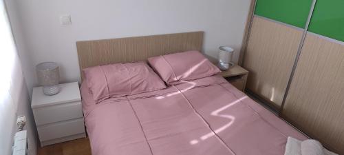 a pink bed with pink sheets in a bedroom at Lux Apartmans in Zagreb