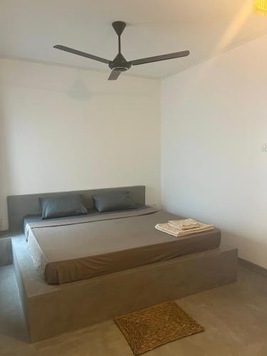 a bedroom with a bed with a ceiling fan at The Drop In Surfhouse Madiha in Madihe East